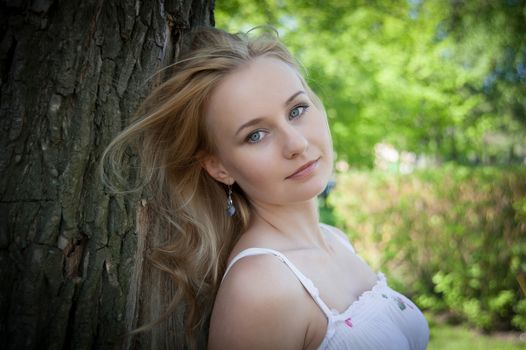 beautiful, young woman standing near the tree in the park