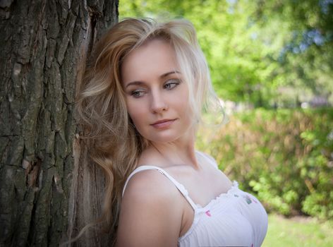 beautiful, young woman standing near the tree in the park