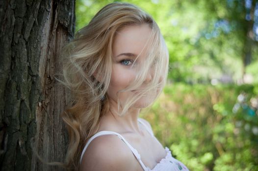 beautiful, young woman standing near the tree in the park