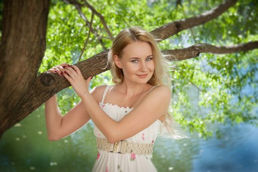 beautiful, young woman standing near the tree in the park