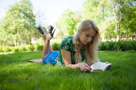 young girl is laying on the grass with a book