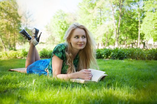 young girl is laying on the grass with a book