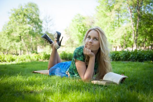 young girl is laying on the grass with a book