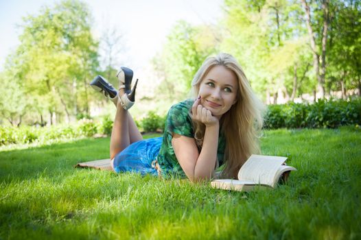 young girl is laying on the grass with a book