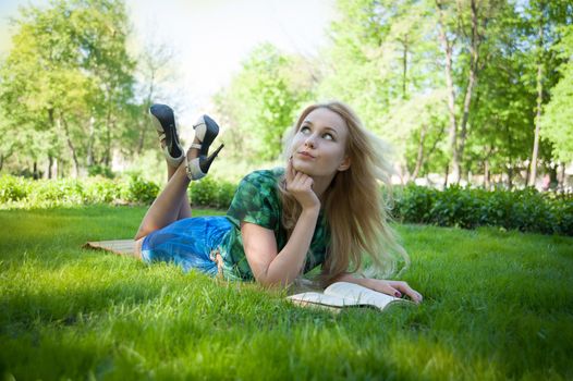 young girl is laying on the grass with a book