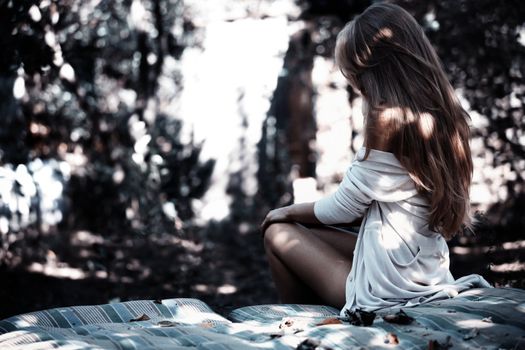 Beautiful lady in white shirt outdoors sitting on a bedding