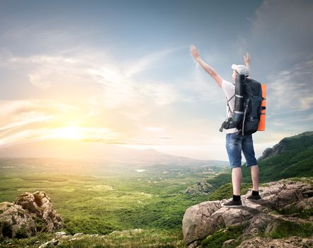 Tourist with backpack enjoy valley view from top of a mountain