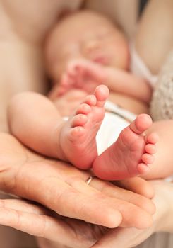 Newborn baby in mother's arms, closeup view, feet in focus