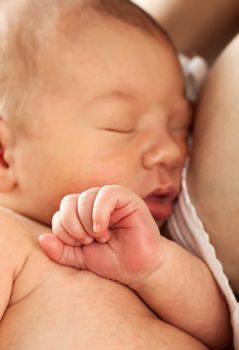 Newborn baby boy sleeping in mother's arm after breastfeeding