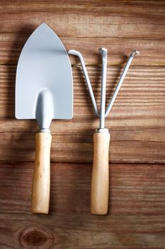 Gardening tools -  a shovel and a rake on a rustic wooden table 