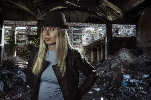 portrait of a young fashionable blonde in ruins of a building covered with garbage