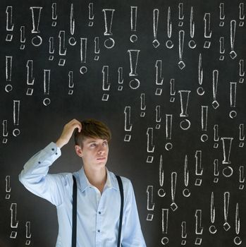 Thinking business man with chalk exclamation marks on blackboard background