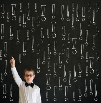 Hand up answer boy dressed up as business man with chalk exclamation marks on blackboard background