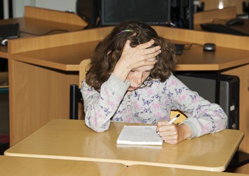 left handed girl writing on paper in school