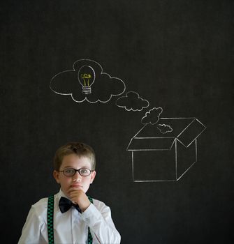 Thinking boy dressed up as business man with chalk thinking out the box concept  on blackboard background