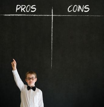 Hand up answer boy dressed up as business man with chalk pros and cons decision list on blackboard background