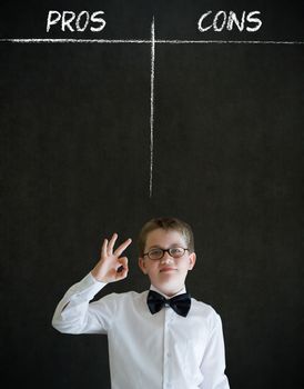 All ok or okay sign boy dressed up as business man with chalk pros and cons decision list on blackboard background