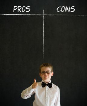 Thumbs up boy dressed up as business man with chalk pros and cons decision list on blackboard background