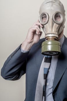 businessman with gas mask with phone on gray background