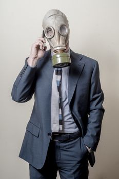 businessman with gas mask with phone on gray background