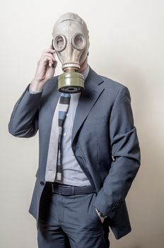 businessman with gas mask with phone on gray background