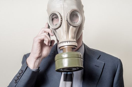 businessman with gas mask with phone on gray background