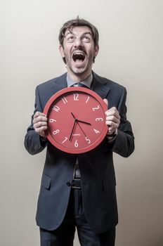 businessman with clock screaming on gray background