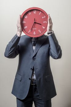 businessman with clock on his head on gray background
