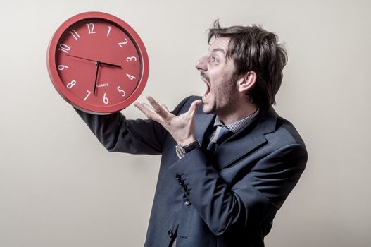 businessman with clock screaming on gray background