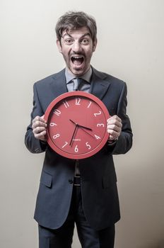 businessman with clock screaming on gray background
