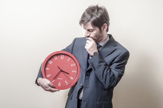 businessman with clock doubtful on gray background