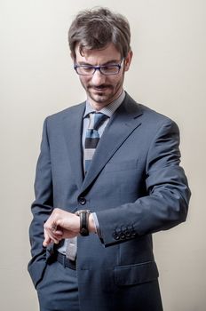 businessman looking wristwatch on gray background