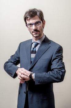 businessman looking wristwatch on gray background