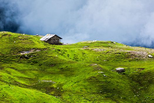 Serenity serene lonely scenery background concept - house in hills in mountins on alpine meadow in clouds