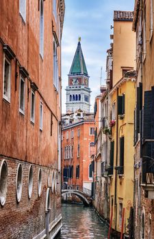 Narrow canal in Venice and st. Marcus bell tower in background 