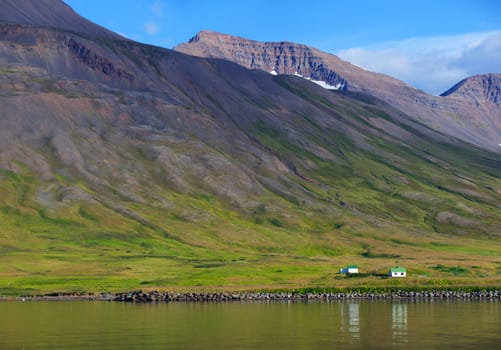 Iceland summer landscape. Fjord, house, mountains. Panorama.