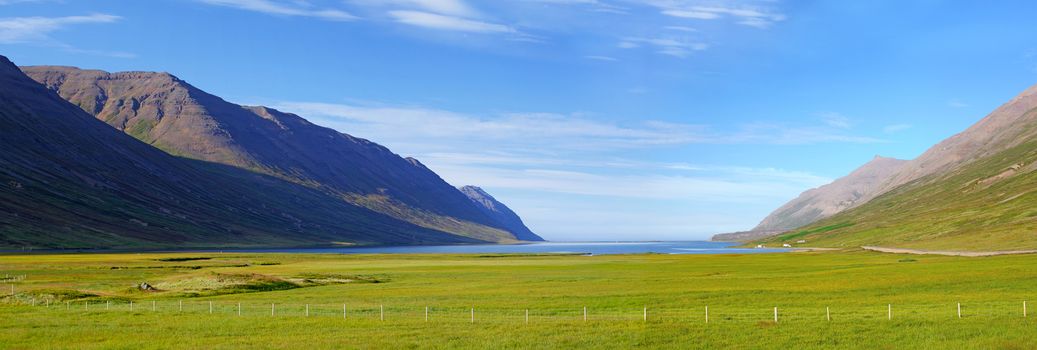 Iceland summer landscape. Fjord, house, mountains. Panorama.