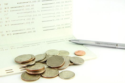 Coins on account passbook with pen on white background
