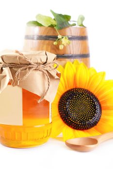 Jar and barrel with honey and flowers isolated on white