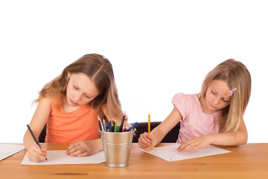 Two concentrated children draw on a wooden table. Isolated on a white background.