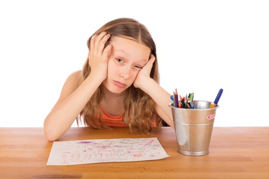 Sad child sitting at a table lack of ideas. Isolated on a white background.