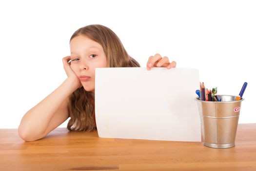 Demoralized child sitting at a wooden table shows a white sheet of paper. Isolated on a white background.