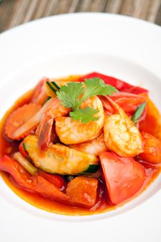 Thai style sweet and sour shrimp dish presented beautifully on a round white plate.