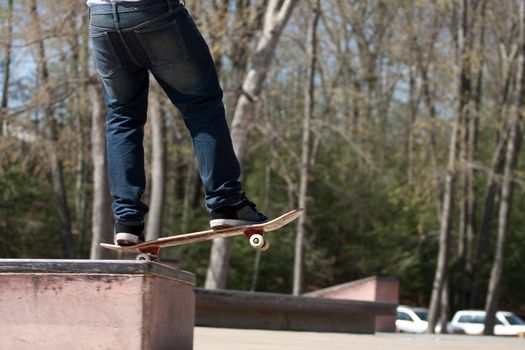 Action shot of a skateboarder skating at the park on a concrete rail.