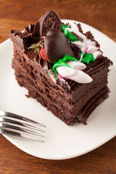 Decadent slice of chocolate cake on a plate with a fork.