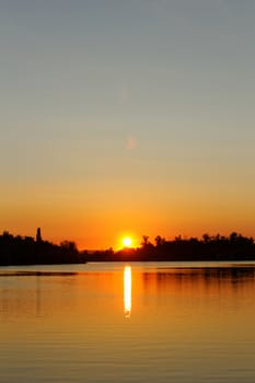 Colorful sunset over tranquil water surface.