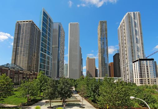 Partial skyline of skyscrapers near the Chicago River in the Loop area at the center of downtown Chicago, Illinois, against a bright blue sky.