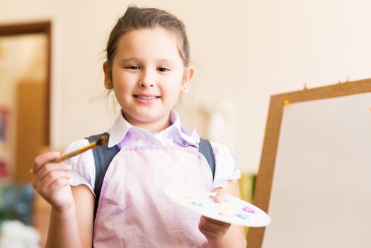 Portrait of Asian girl in apron interested in painting at an art school