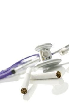 Cigarettes with stethoscope in background. Isolated over white background.