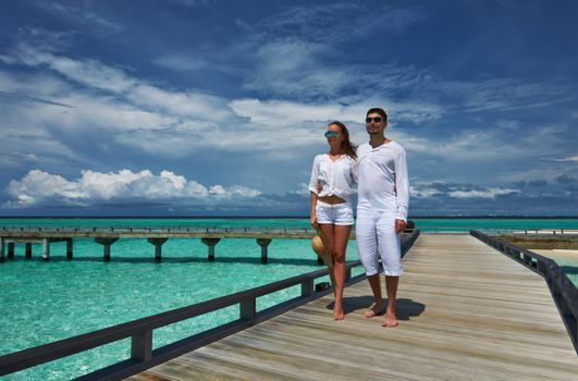 Couple on a tropical beach jetty at Maldives